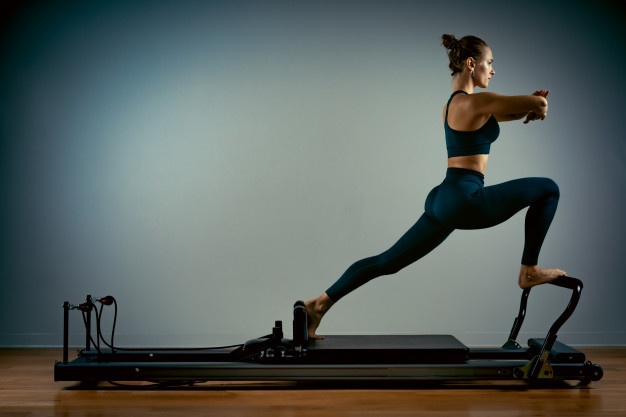 woman performing a Pilates exercise on a Reformer